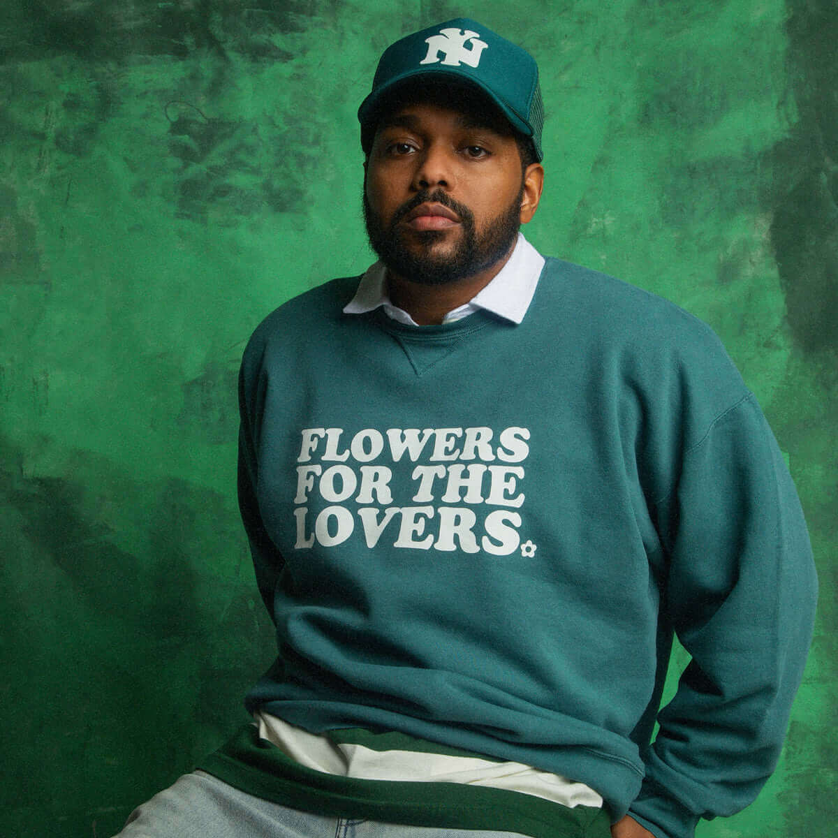 Model wearing a flowers for the lovers sweatshirt by Steven Othello against a green background.