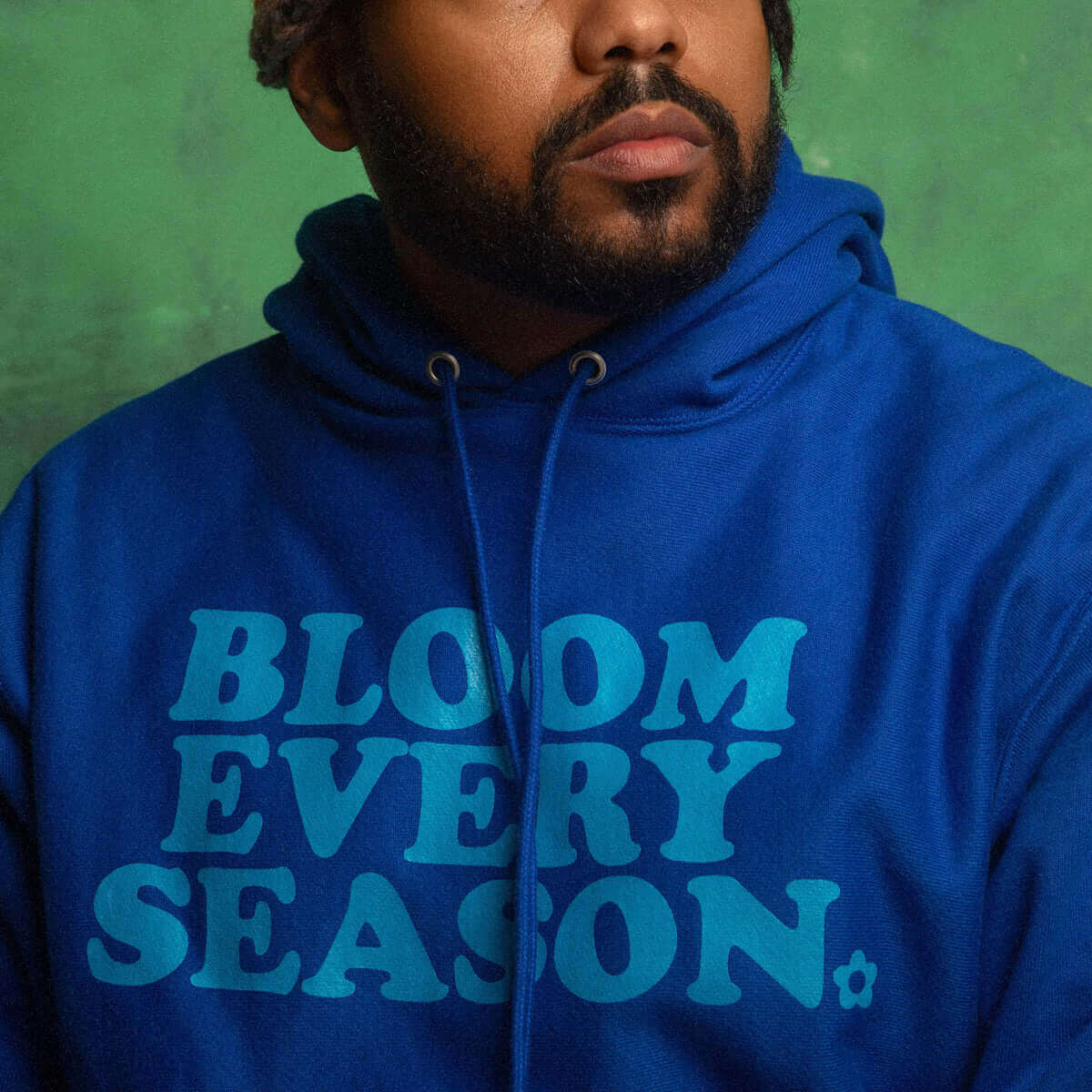 Bloom Every Season hoodie displayed by model, featuring bold graphic on rich blue fabric, showcasing soft style and comfort.